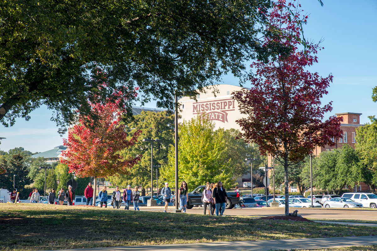 Colorful red trees with students walking in the Junction near Davis Wade Stadium
