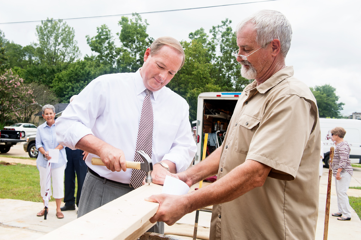 President Keenum using a hammer to drive the first nail on the new Habitat for Humanity house.
