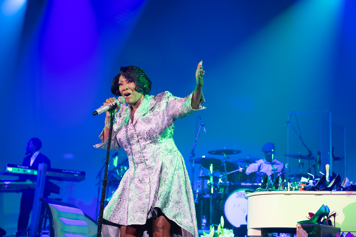 Singer in sparkly dress singing on stage with blue lights