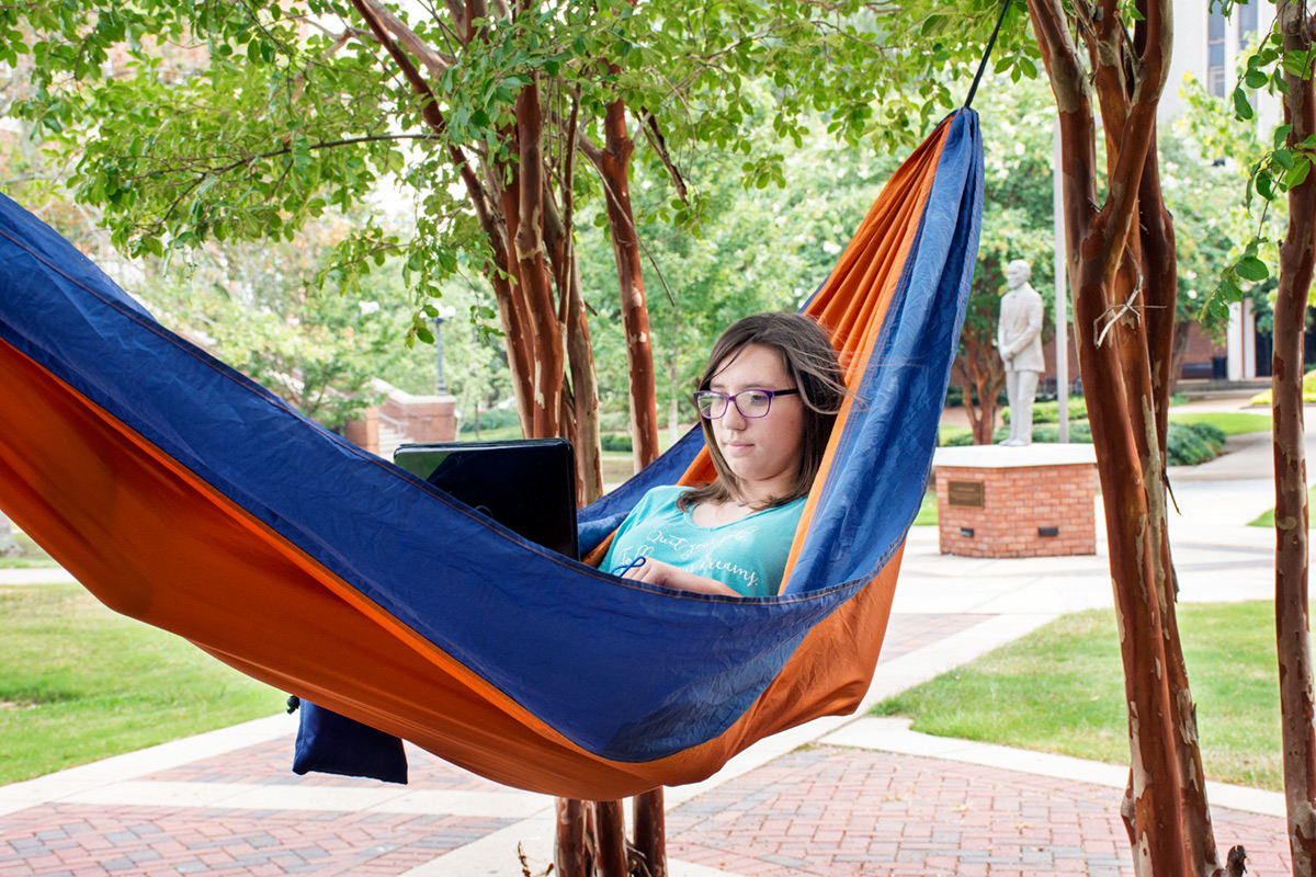 Female student studying with laptop in a hammock