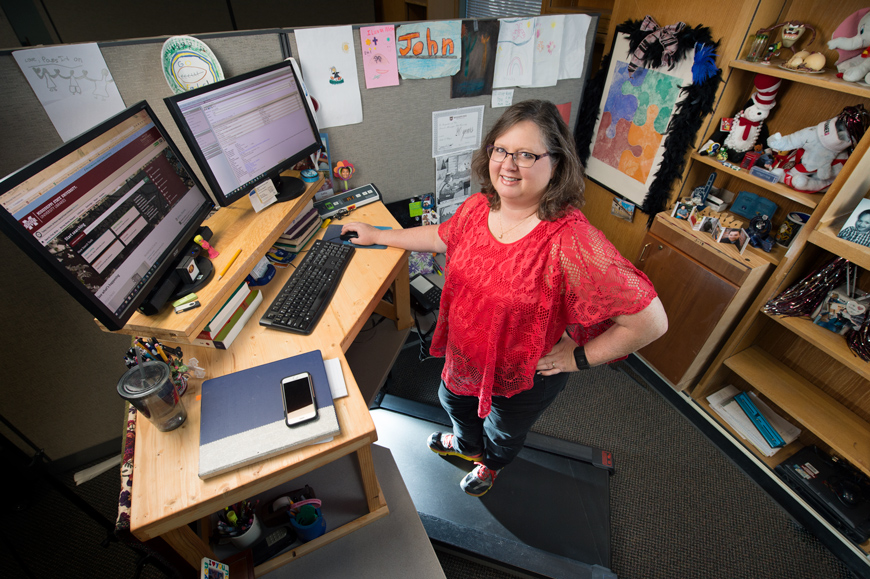 Anita Winger stands on her treadmill at her office space in Mitchell Memorial Library.