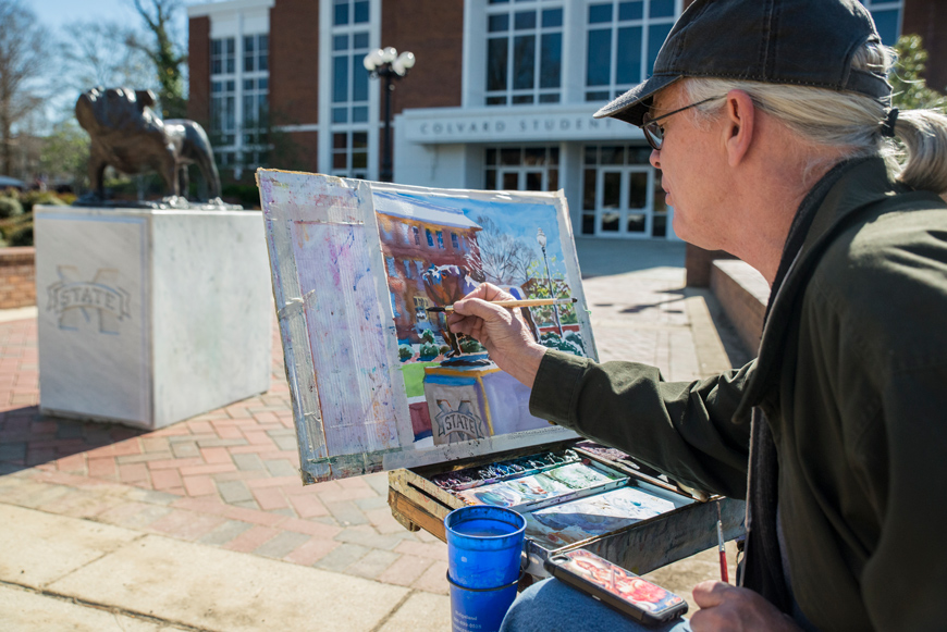 Artist Wyatt Waters sits in front of a Bully statue, painting the scene.