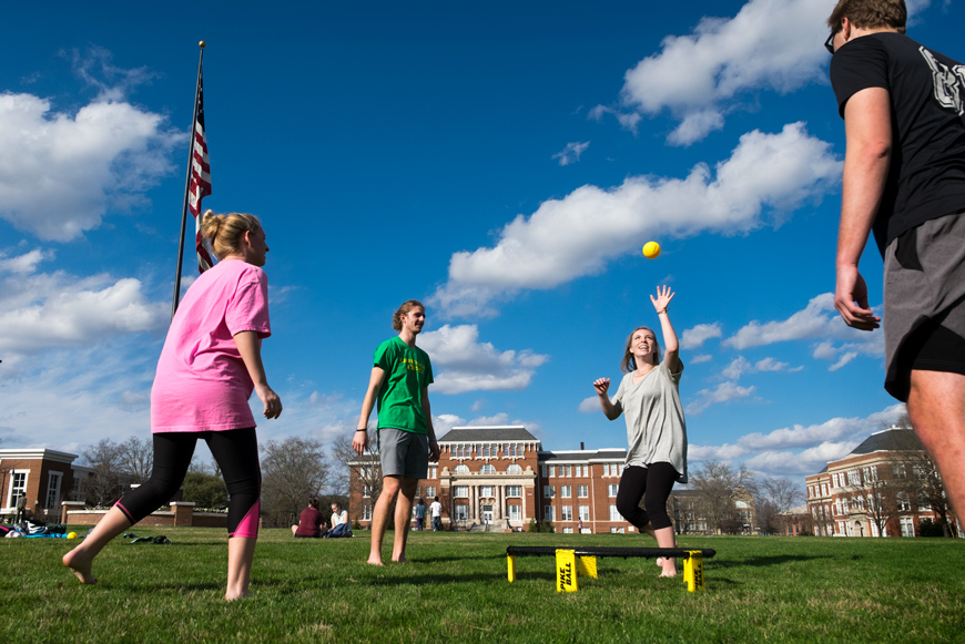 Four MSU students play spikeball on the Drill Field on a sunny day.