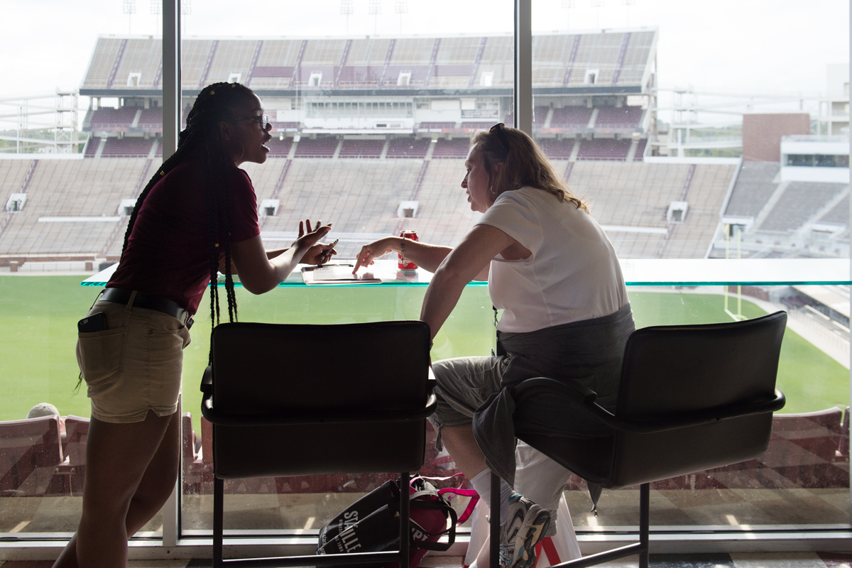 With the empty Davis Wade Stadium as a backdrop to a Freshman Orientation dinner, a Dining Services employee speaks to a mother.