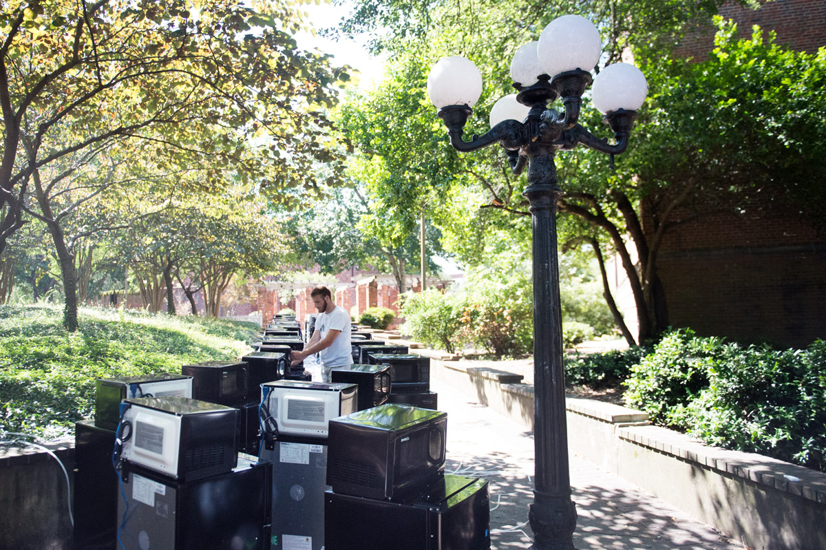 A worker counts dozens of dorm sized fridges and microwaves, lined up on a sidewalk near the Chapel of Memories.