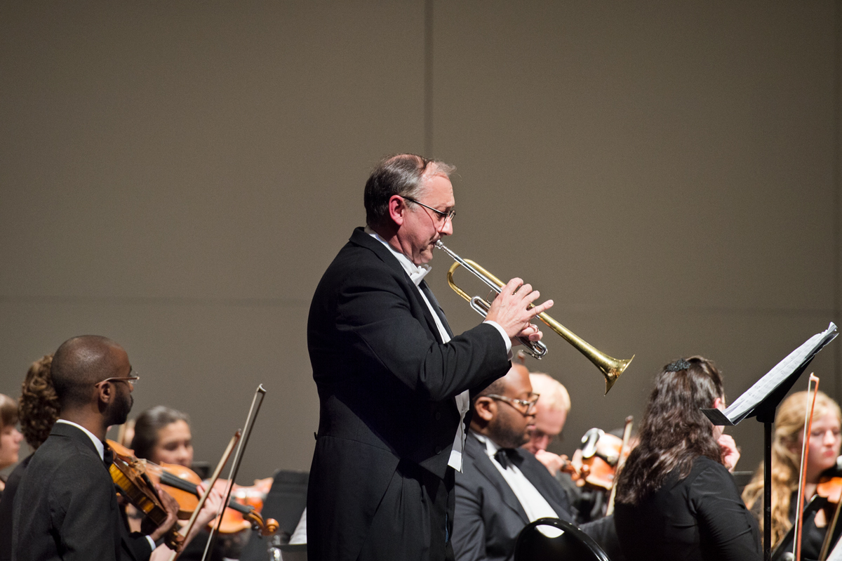 Music professor Anthony Kirkland plays trumpet with Starkville-MSU Symphony Orchestra in background.