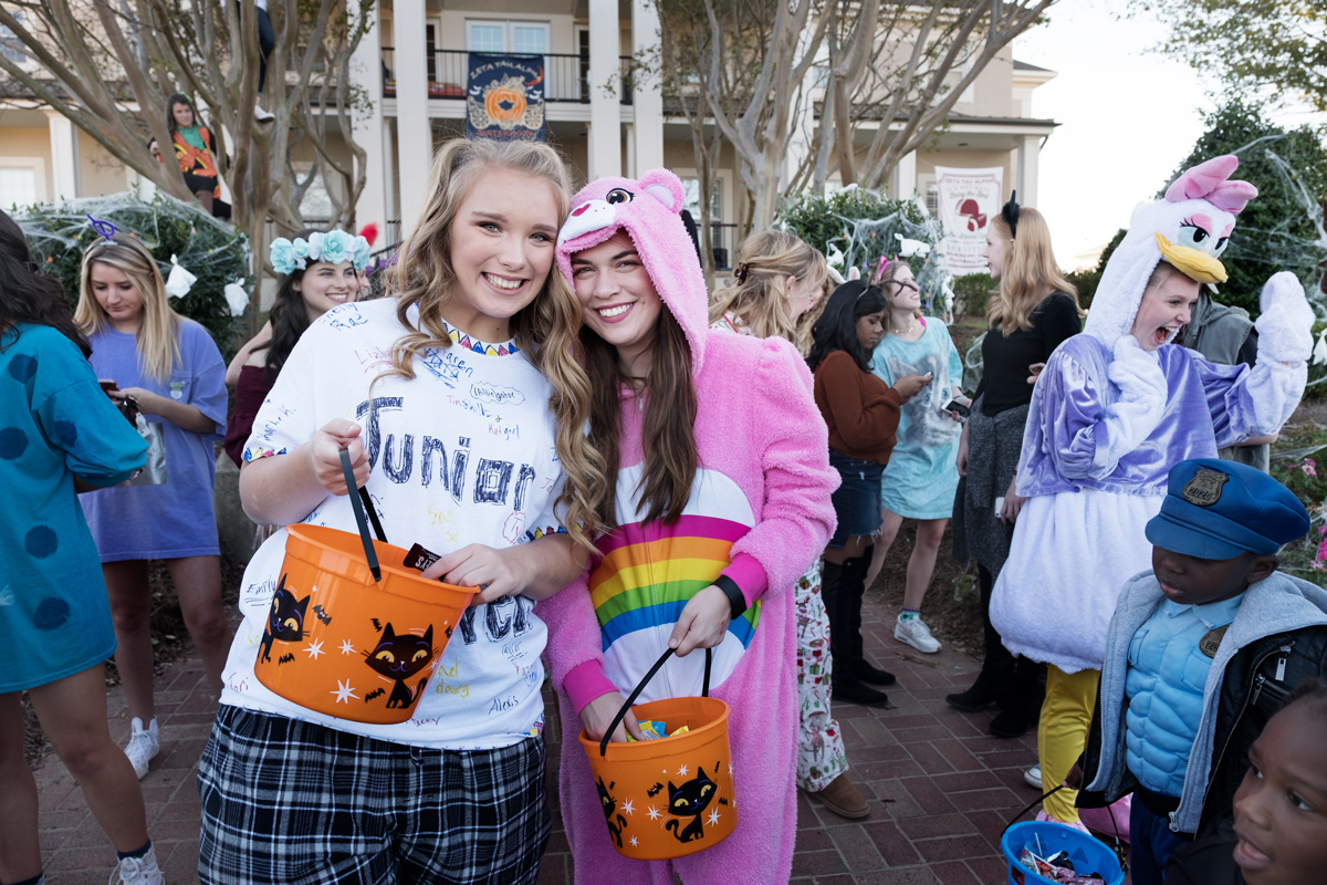 Two students smile as the give out candy in front of Zeta Tau Alpha.