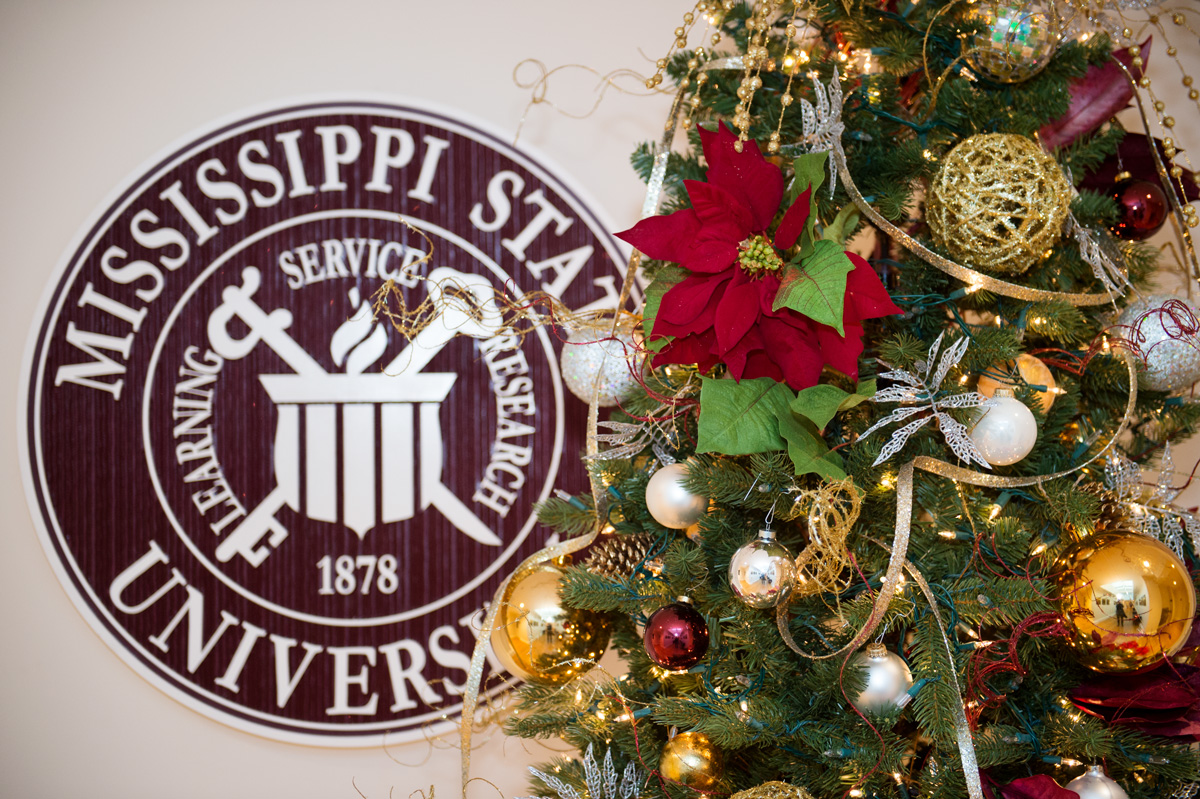 Tight photo of Christmas tree with MSU seal behind it.
