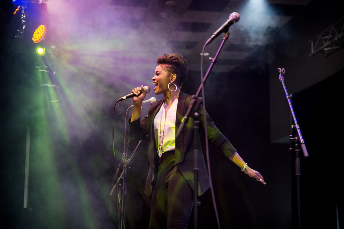 MSU Alum Jasmine Murray sings on the stage with spotlights and smoke.