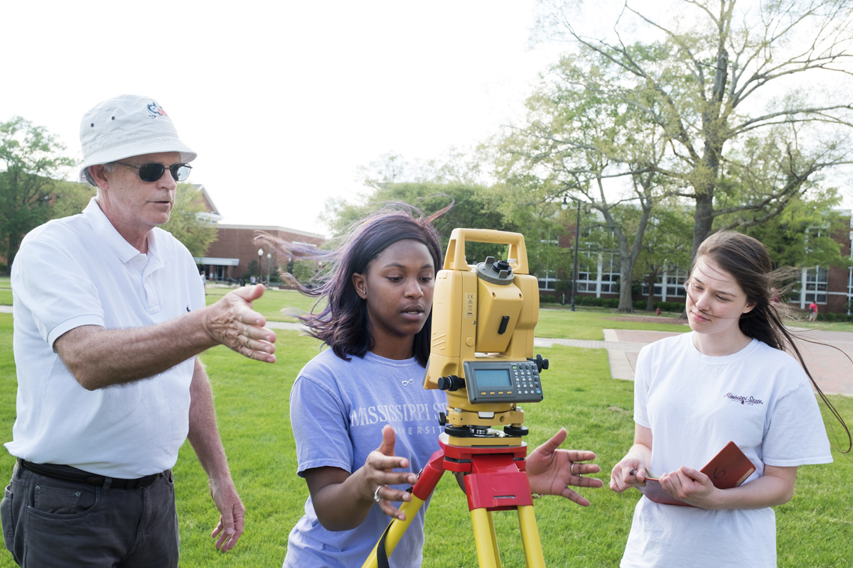 Civil Engineering Instructor Hub King supervises two class students as they learn how to adjust their surveying equipment.
