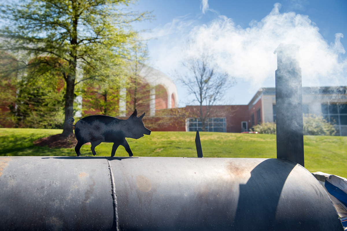With Humphrey Coliseum in the background, smoke emerges from a gill decorated with a metal pig.