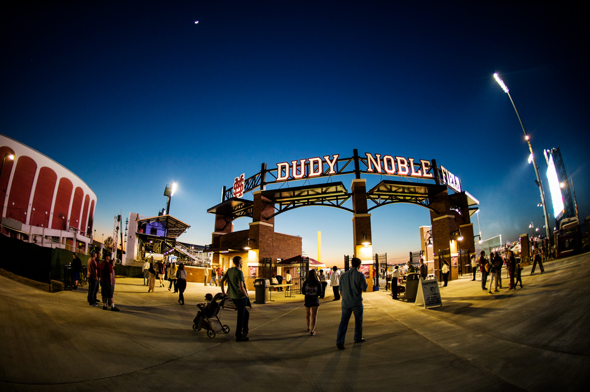 Baseball fans entering Dudy Noble Field at sunset.