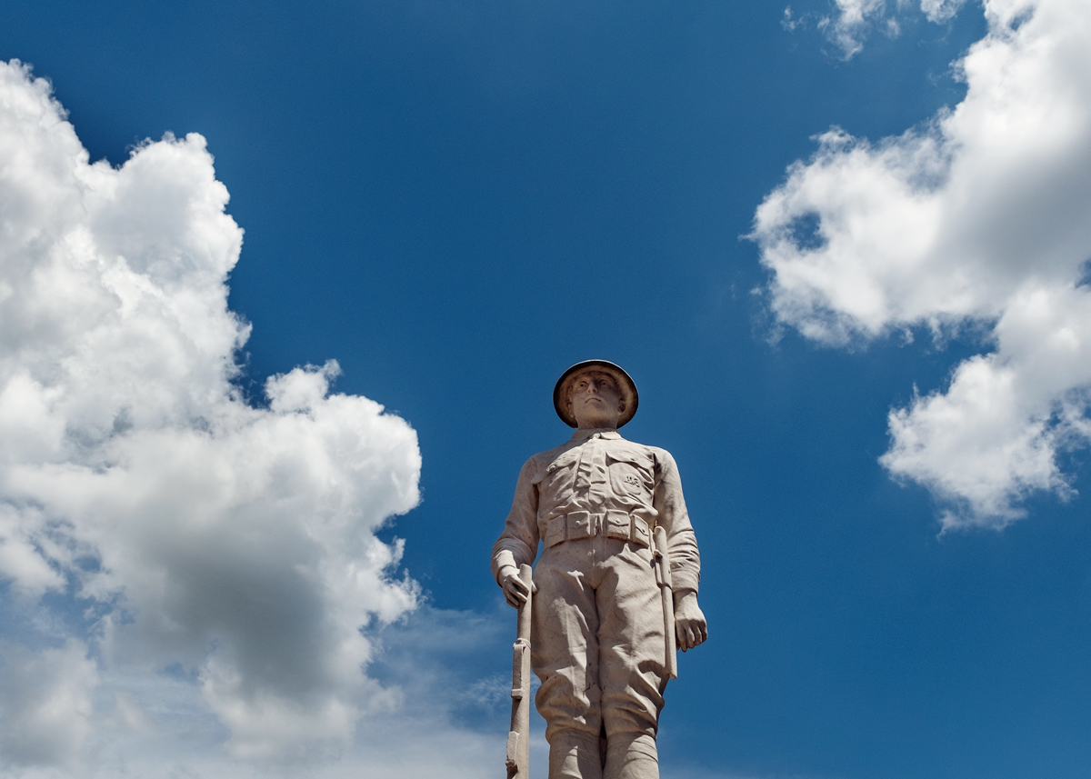 The WWI Memorial statue is framed by blue sky and cumulus clouds.