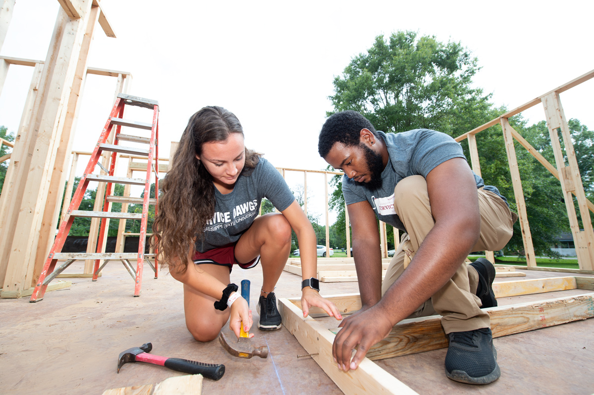 Service DAWGS Day volunteers Amanda Wilson and Lewis Smith work together to hammer a wall at the Habitat for Humanity House.