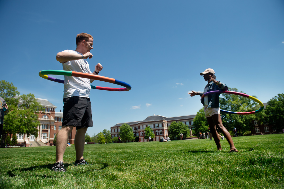 Students Tryce Lawler and Kabriana Kirk take a break from studying by hula hooping on a Drill Field sunny day.