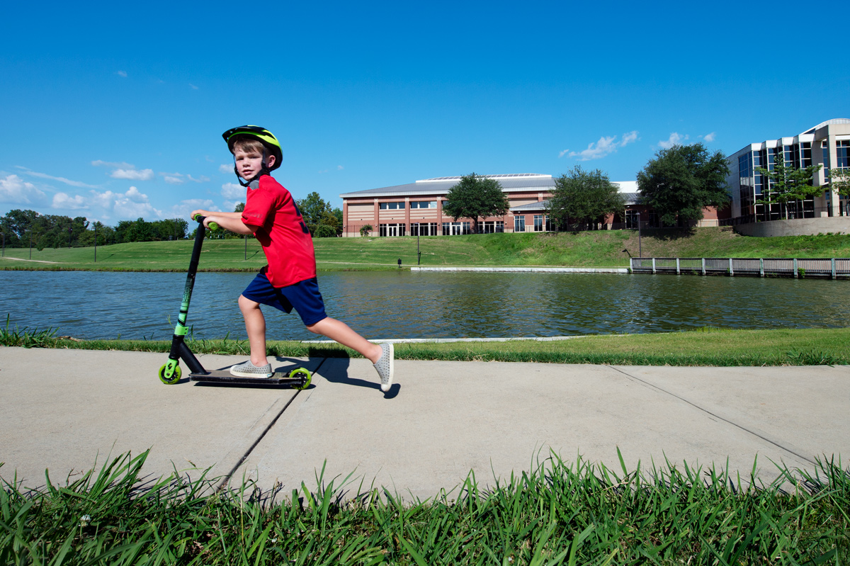 Six year old Jax Looney skooters past on the Chadwick Lake Walking Trail on a beautiful summer day.