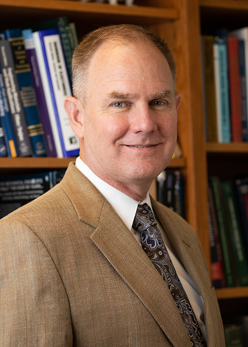 J. Alex Thomasson, pictured in front of shelves full of books