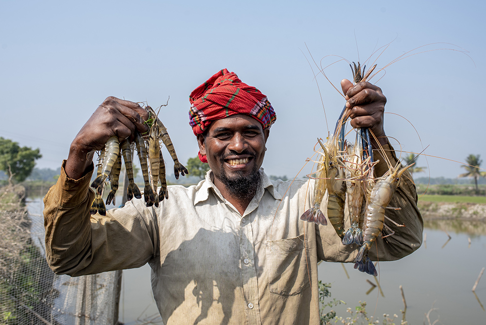 A man holds up prawns 