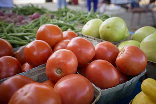 Farmers market table with green and red tomatoes and green beans