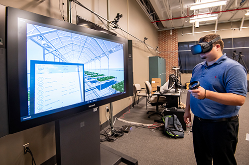 Christopher Hudson, a computer science doctoral student in Mississippi State’s Bagley College of Engineering, tests out a beta version of the future grower technology designed to help students better learn how to master environmental controls. (Photo by David Ammon)