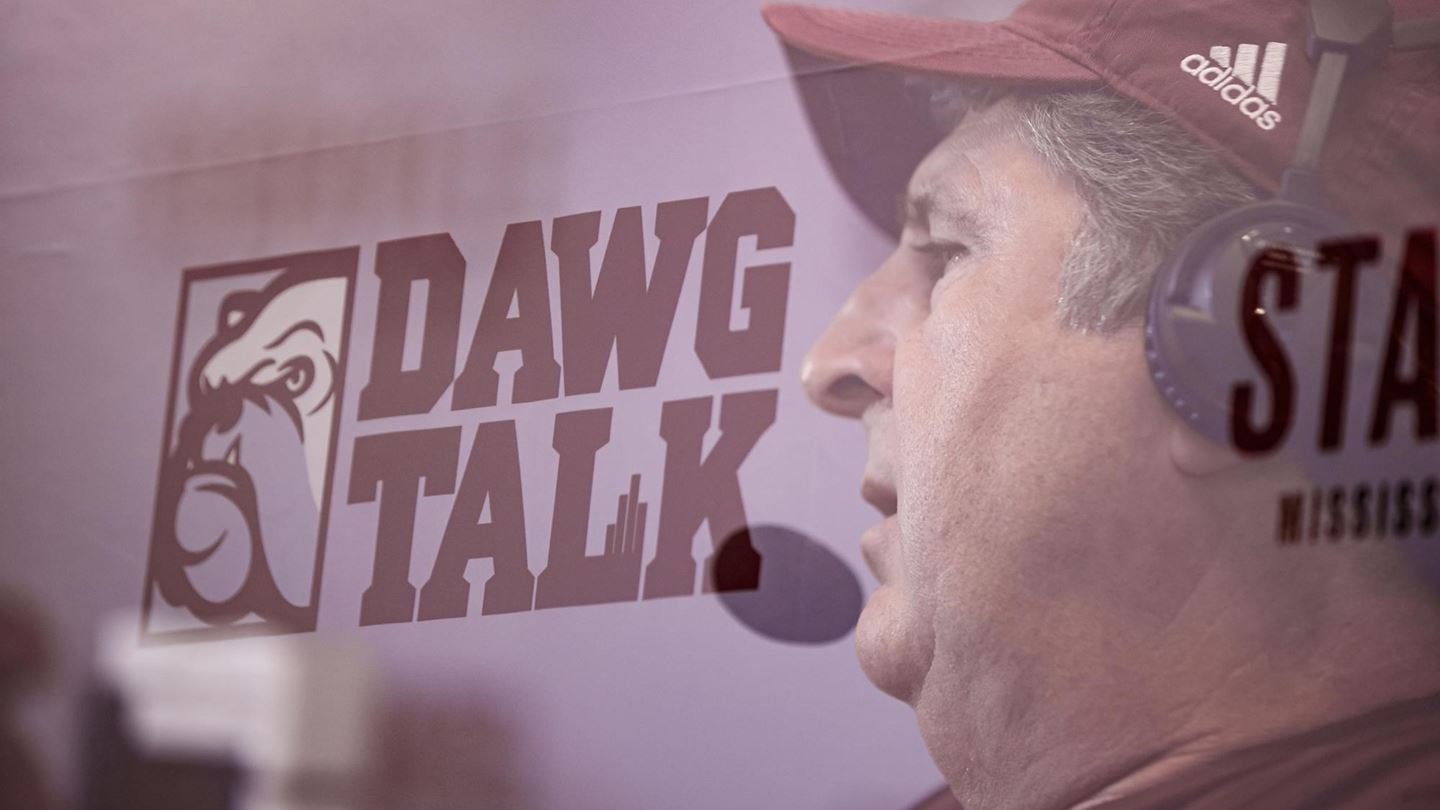Image of Coach Mike Leach wearing a maroon Adidas hat and black headphones with the Dawg Talk bulldog logo in the background