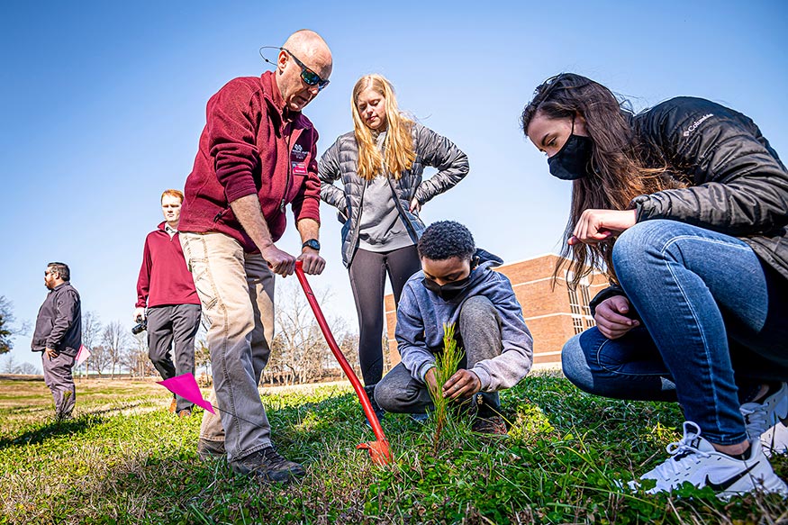 Marc Measells, senior Extension associate, helps Tiwan Triplett, a sixth-grade student from the Partnership Middle School, plant a loblolly pine in celebration of Arbor Day. 