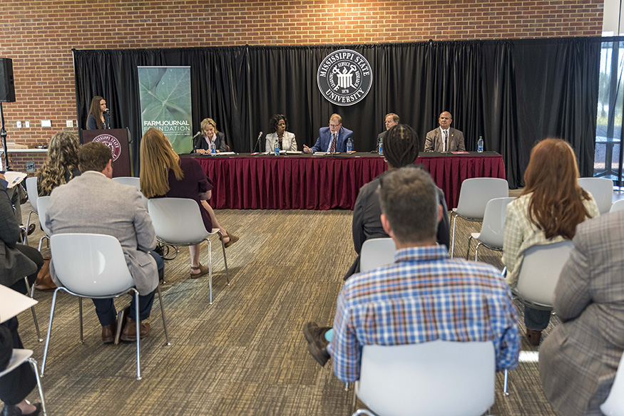 Panel members speak at a table at MSU