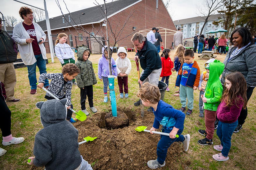 MSU College of Forest Resources Dean Wes Burger plants a redbud tree with children from the university’s Child Development and Family Studies Center. 