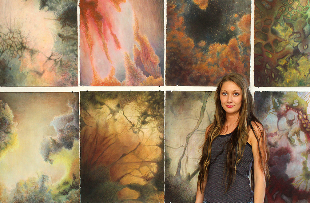 MSU senior Victoria Cheek of Kosciusko stands before her mixed-media painting collection titled "One Indivisible Whole." It is among several student creations being featured this month in the art department's Bachelor of Fine Arts Thesis Exhibition. 