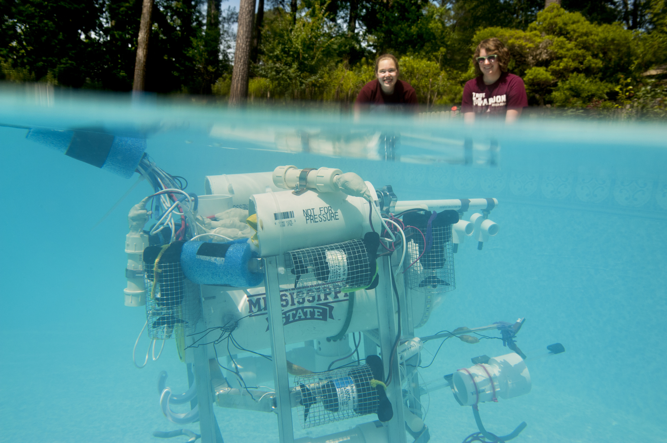 Amelia Hebert and Anna Purser look over a swimming pool where their team's ROV is submerged during testing prior to their travels this week to the 2015  MATE Competition: Science and Industry in the Arctic.