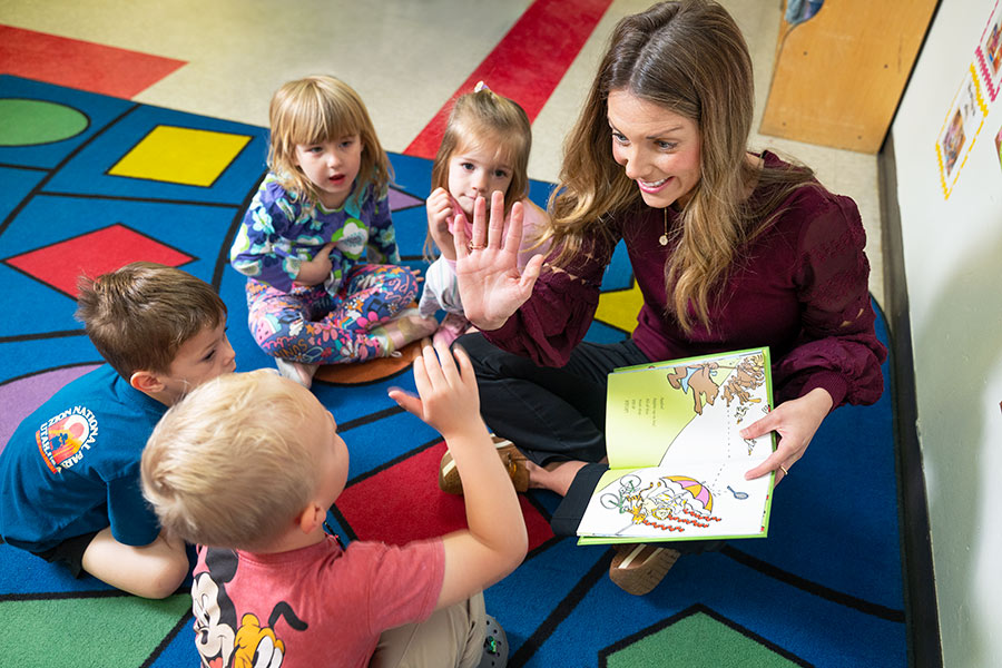 MSU Mary Hannah Mills reading a book to a group of children on the floor