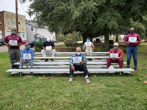 Several people hold signs that say "I am change in Mississippi" as they gather in a local park area