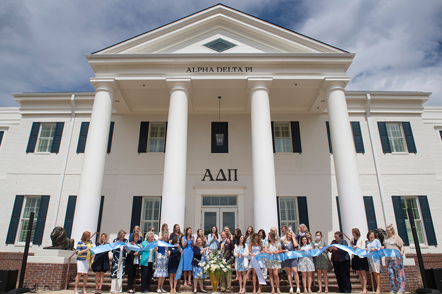 A crowd gathers to cut a ribbon and celebrate the opening of the new Alpha Delta Pi house on the MSU campus.
