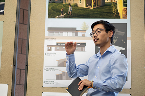 Michael Chew, a senior architecture student from Birmingham, Alabama, stands in front of his team’s board to present their housing design. 