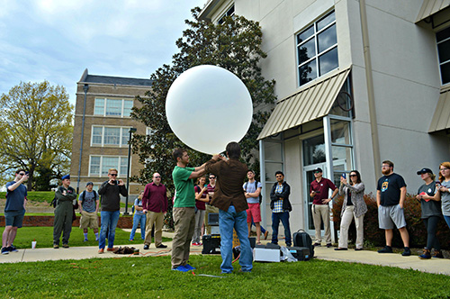 Members of the East Mississippi NWA and AMS chapter look on as MSU graduate student Reginald Roakes of Moundville, Alabama, and a representative from Vaisala Corp. launch a balloon to take atmospheric measurements above the Starkville campus in March 2018. (Photo submitted)