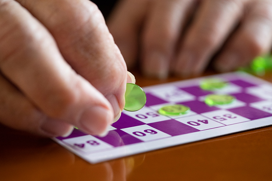 A close-up of an elderly person's hands while playing a game of bingo