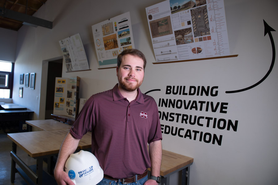 Jack Blacklock in an MSU T-shirt, holds a Brassfield & Gorrie hard hat