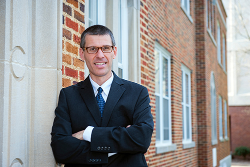 Portrait of Stephen Brain standing next to a brick building