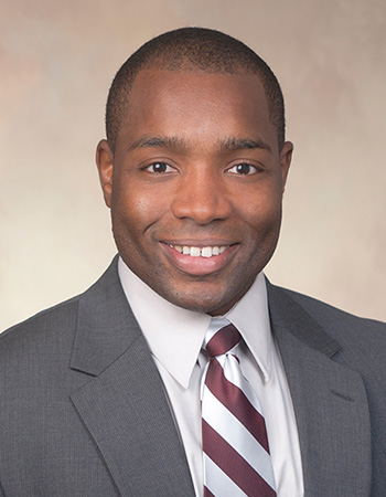 Portrait of Brian Pugh, he is wearing a suit jacket and a maroon and white diagonally striped tie