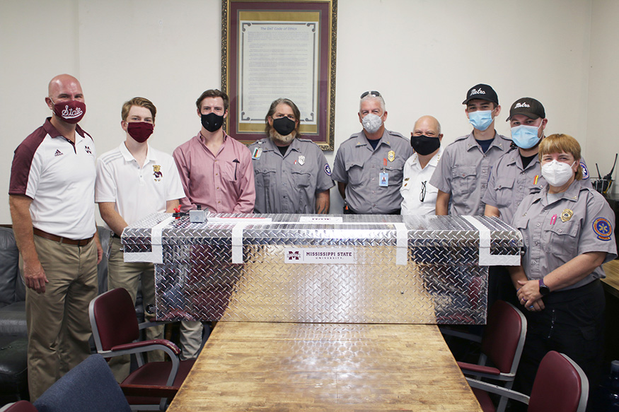 MSU and Metro Ambulance Personnel take a photo around the mask disinfectant box