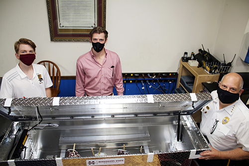 Justin Easley, Ryden Smith and Clayton Cobler photographed around the mask disinfectant device