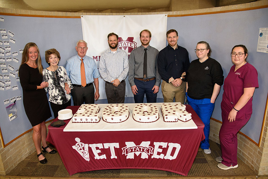 Team members working with Mississippi State’s Shelter Medicine Program in the College of Veterinary Medicine, pictured with donor Marcia Lane, second from left, and a cake celebrating the 100,000th surgery milestone, include (l-r) Dr. Kimberly Woodruff, Dr. Phil Bushby, Dr. Brookshire Cooper, Dr. Alex Shealy, Dr. Jake Shively, and Veterinary Technicians Emily Childers and Paula Morgan. 