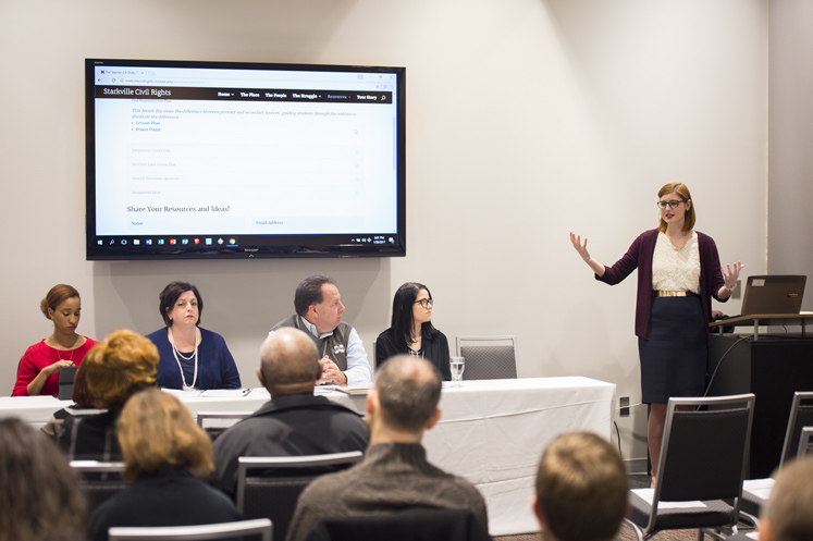 Christine Dunn speaks from a podium beside forum panelists. Mississippi State University senior Christine Dunn, a secondary education major from Niceville, Florida, discusses lesson plans she created as part of the Starkville Civil Rights project. (Photo by Russ Houston)