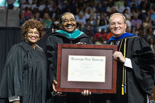 Mississippi State President Mark E. Keenum, right, presents an honorary Doctor of Public Service degree to Robert G. Clark Jr., former Speaker Pro Tempore of the Mississippi House of Representatives, during the university’s spring commencement ceremonies. Looking on is Clark’s wife, JoAnn Ross Clark. (Photo by Megan Bean)
