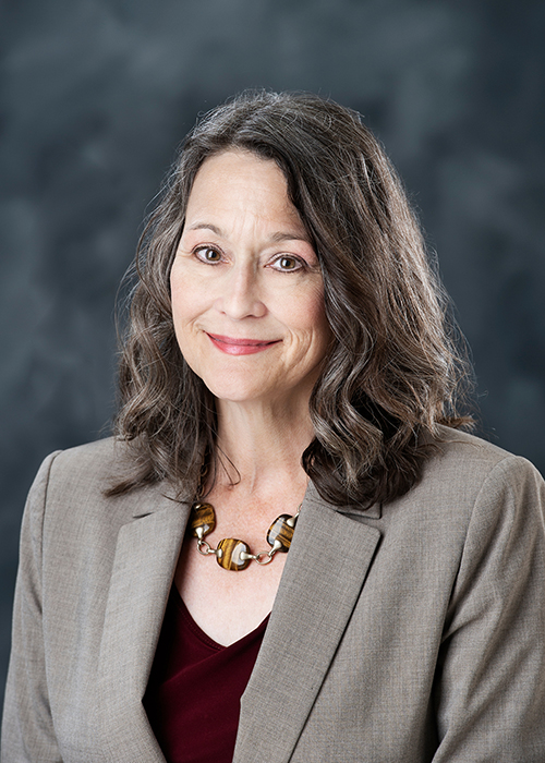 Studio portrait of Renée M. Clary in a maroon blouse and grey blazer