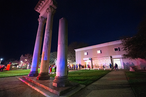 Columns in front of the Cobb Institute are illuminated as Science Night attendees can be seen in the background