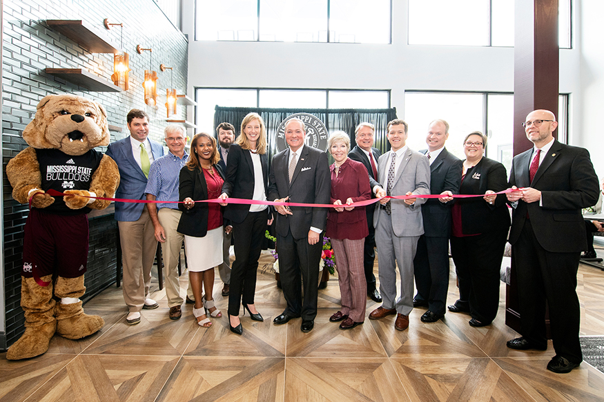 Mississippi State and Greystar officials cut a ribbon to mark the completion of the College View student housing development, which includes over 650 residential beds and 46,000 square feet of residential space. Pictured, from left, are MSU’s Bully mascot, Hanbury Principal and Planner Reid Sabin, Montgomery Martin Contractors Vice President Jeff Emerson, MSU Director of Housing and Residence Life Dei Allard, McCarty Architects Architectural Team Leader Justin Harrington, Greystar Senior Managing Director of University Partnerships Julie Skolnicki, MSU President Mark E. Keenum, Starkville Mayor Lynn Spruill, Greystar Vice President for Real Estate Development Mark Grambergs, MSU Student Association President Jake Manning, MSU Fiscal Operations Analyst Les Potts, MSU Vice President for Student Affairs Regina Hyatt and MSU Vice President for Finance and Chief Financial Officer Don Zant. (Photo by Beth Wynn)