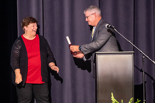 Jim Martin presents a cowbell to Lynne Clark during the Executive Leadership Forum