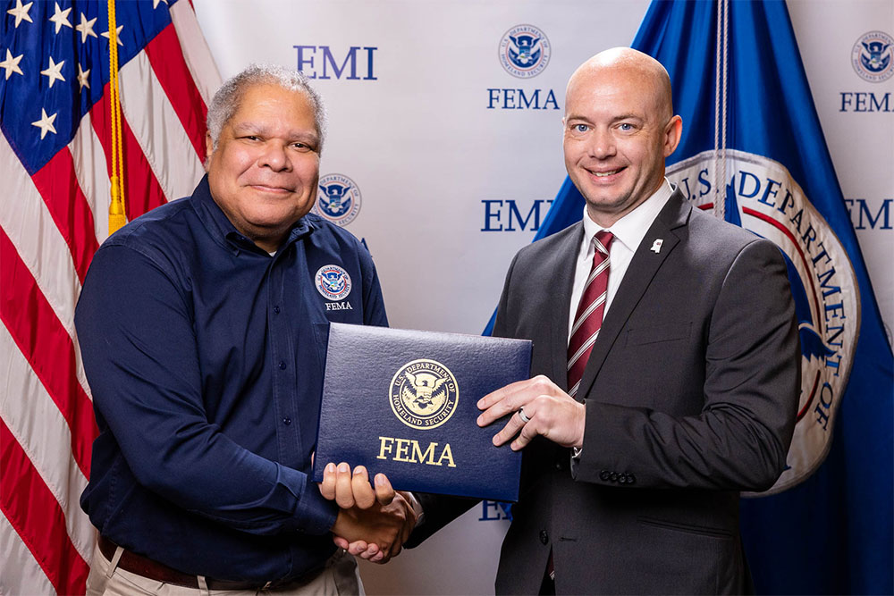 Brent Crocker accepting his graduation certificate from Assistant Administrator of the National Preparedness Directorate Damon Penn. 