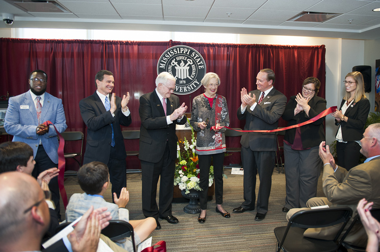 Mary Ann Deavenport cuts the ribbon during the dedication ceremony for Earnest W. and Mary Ann Deavenport Hall on Friday [Oct. 7] at Mississippi State. Pictured, from left to right, are Resident Hall Association President Nicolas Harris, Starkville First Presbyterian Church Senior Pastor Martin Lifer, Earnest W. Deavenport Jr., Mary Ann Deavenport, MSU President Mark E. Keenum, MSU Vice President for Student Affairs Regina Hyatt and MSU Student Association President Roxanne Raven. (Photo by Russ Houston)